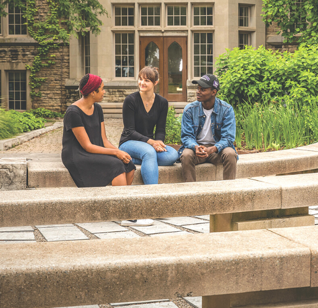 Three students sitting outside talking