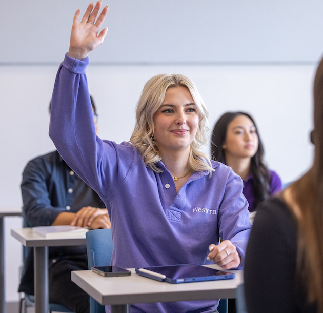 A student raising their hand and smiling