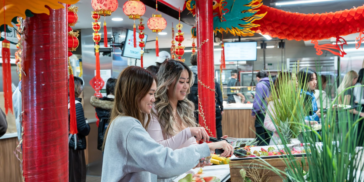 Two Western students in residence dining hall during the Lunar New Year celebration enjoying cultural foods.