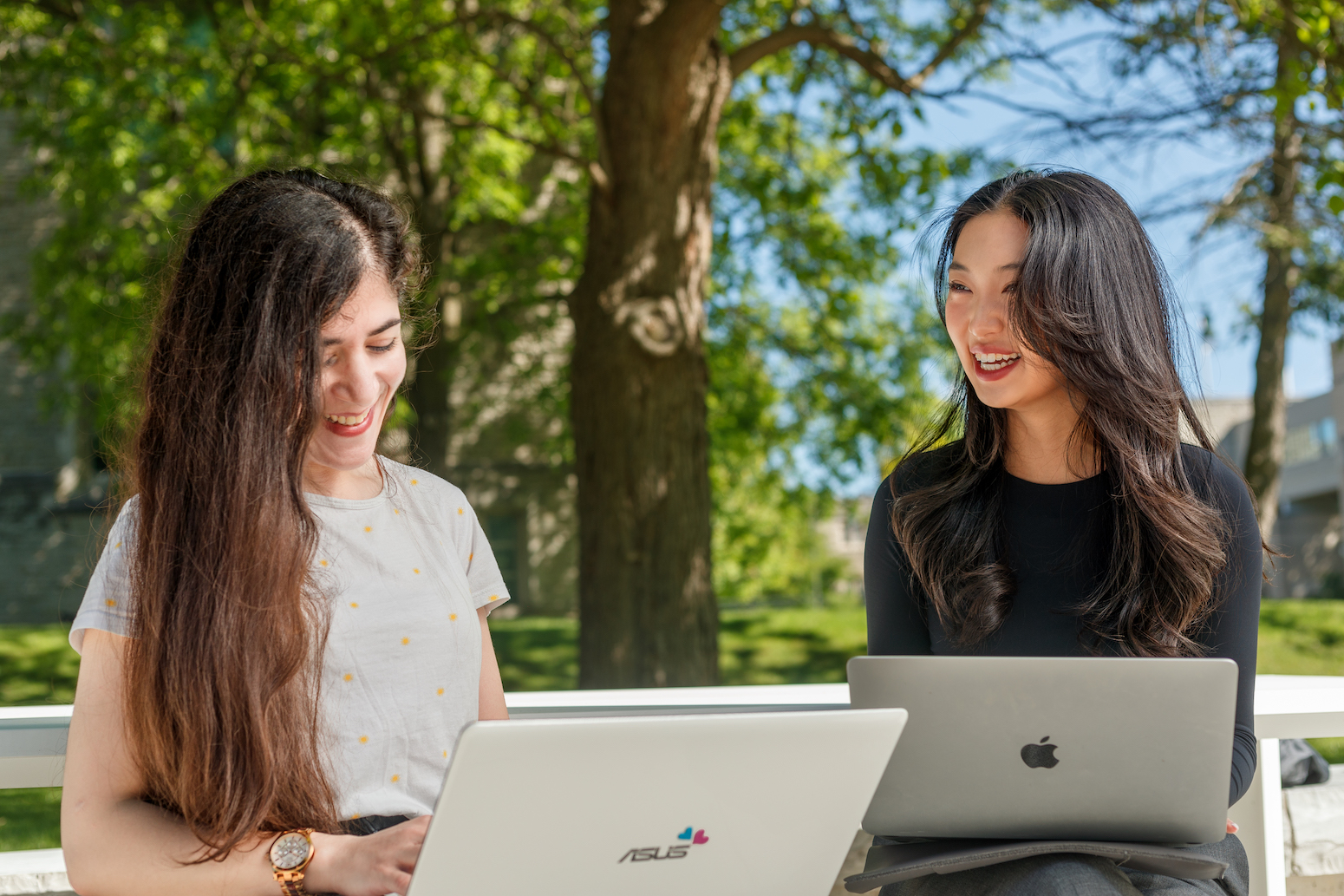 Two students with laptops in the sunshine on Western's campus