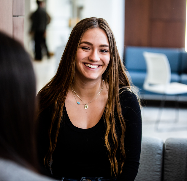 Student sitting in lounge area smiling at camera